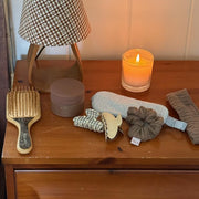 assorted emi jay hair care and accessories on side table with candle and lamp