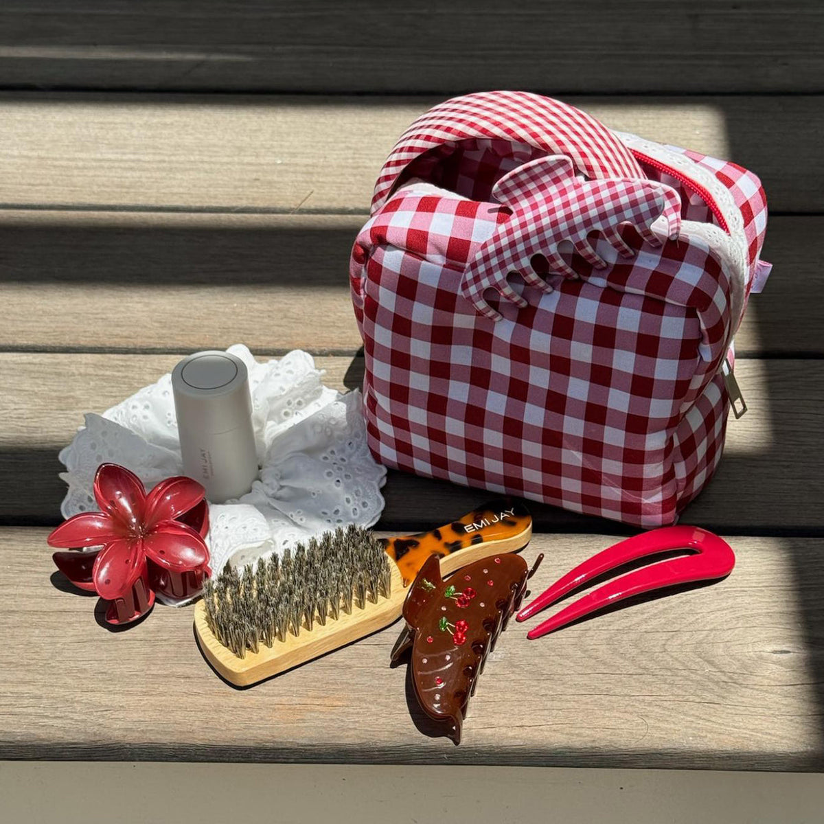 Gingham Pouch in Cherry Kiss on wood with assorted hair care, accessories, and styling tools