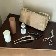 Assorted Emi Jay hair care and accessories with styling tools and bag on table.