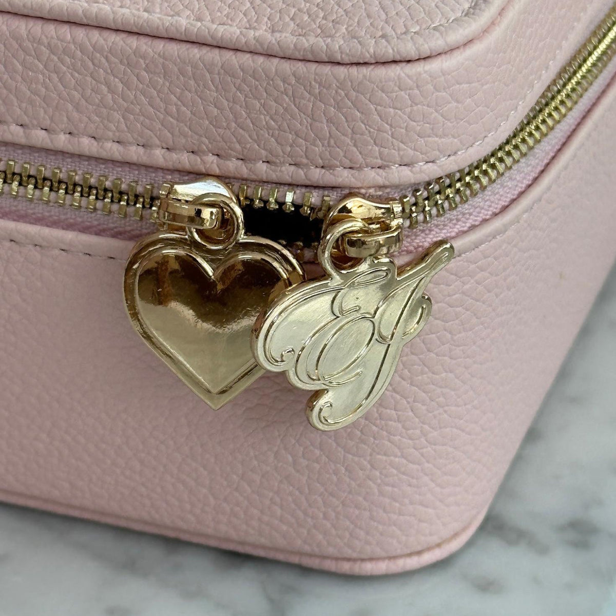 closeup view of charms on On The Way Vanity Case zipper