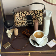 Assorted Emi Jay hair care and accessories with purse and coffee on table.