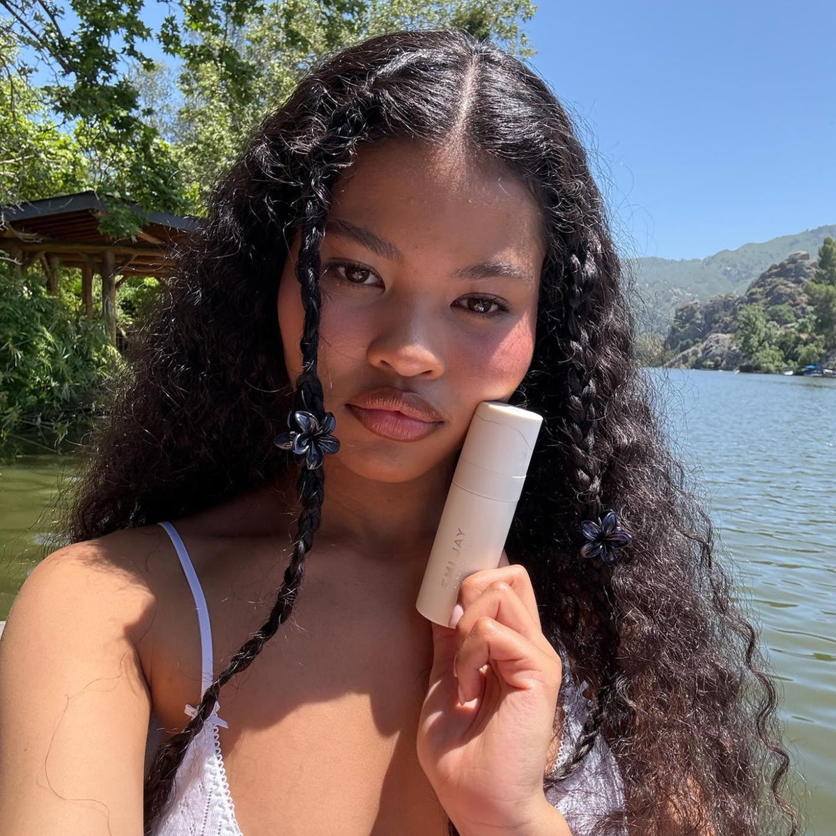 model holding aura hair mist against cheek while wearing Baby Super Bloom Clip Set in Blackberry in hair