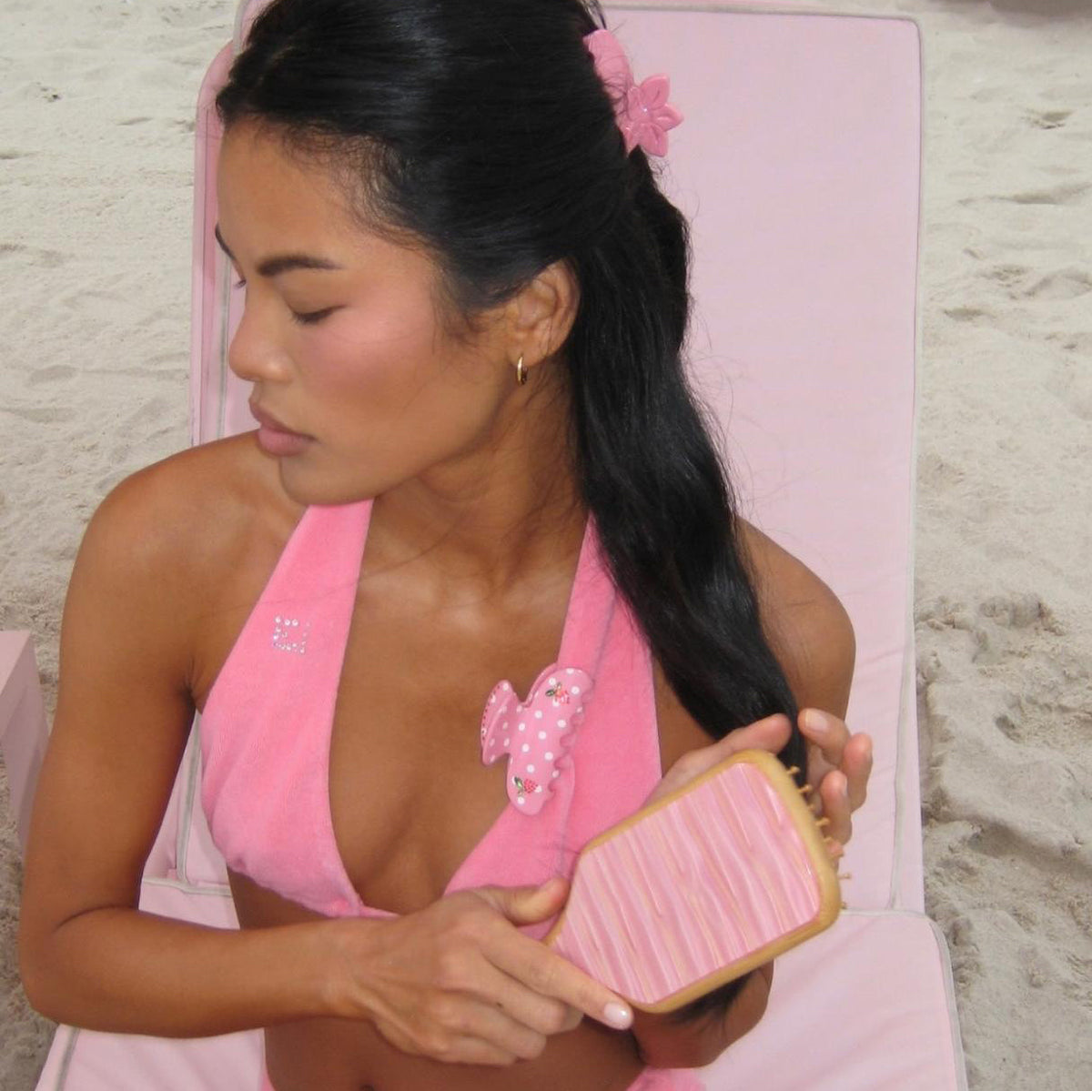 model wearing hair pin brushes hair with Bamboo Paddle Brush in Lychee Baby