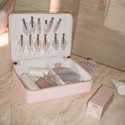 assorted emi jay hair care and accessories in vanity case next to big effing clip and angel hold on marble counter