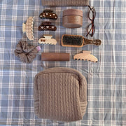 Cozy Pouch in Cookie Crumbs Knit next to assorted hair care, accessories, mini boar brush, and glasses