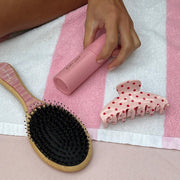 model holding aura hair + body mist in lychee baby next to claw clip and hair brush