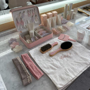 assorted emi jay hair care and accessories on counter with emi jay towel, coffee, and vanity case
