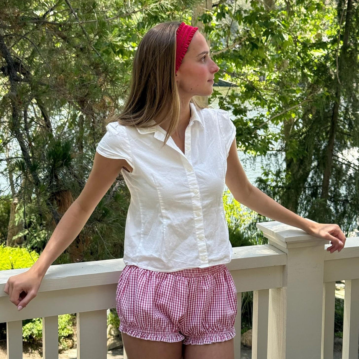 model looking off into distance while standing against railing with Ruffle Headband in Cherry Kiss in hair