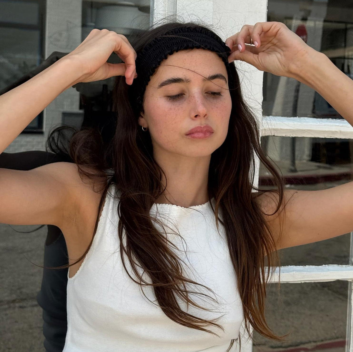 model adjusting Ruffle Headband in Noir in hair