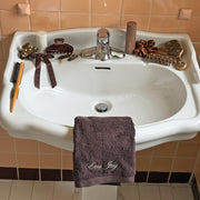Sink with Emi Jay embroidered towel and assorted Emi Jay hair care, accessories, and styling tools sinkside.